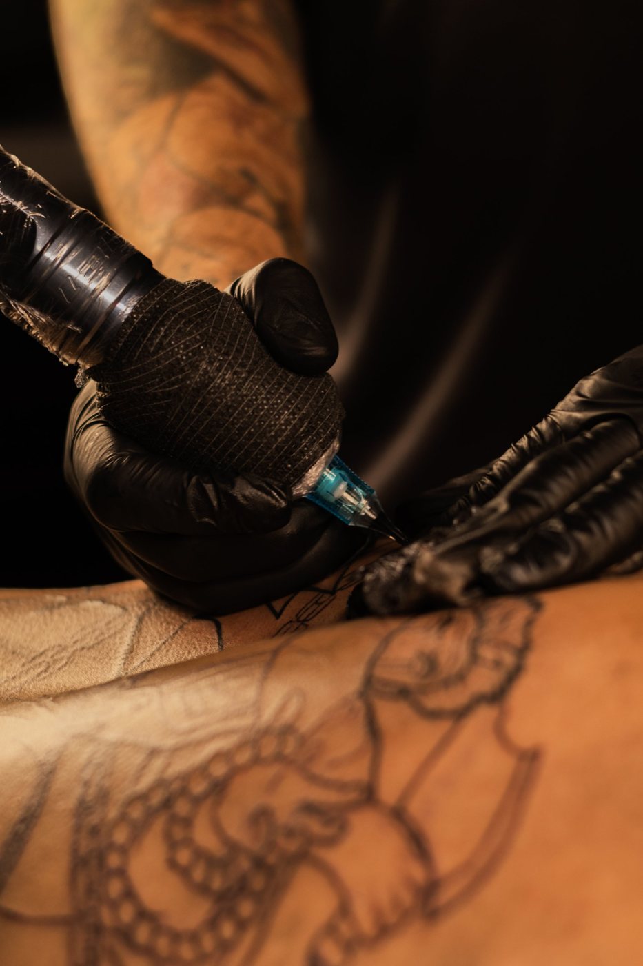 Mãos do Japa tatuando, com luvas pretas